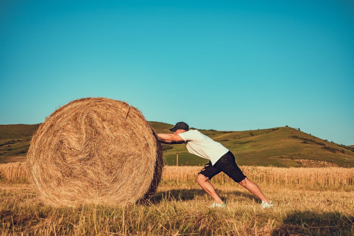 photo of man pushing hay bale