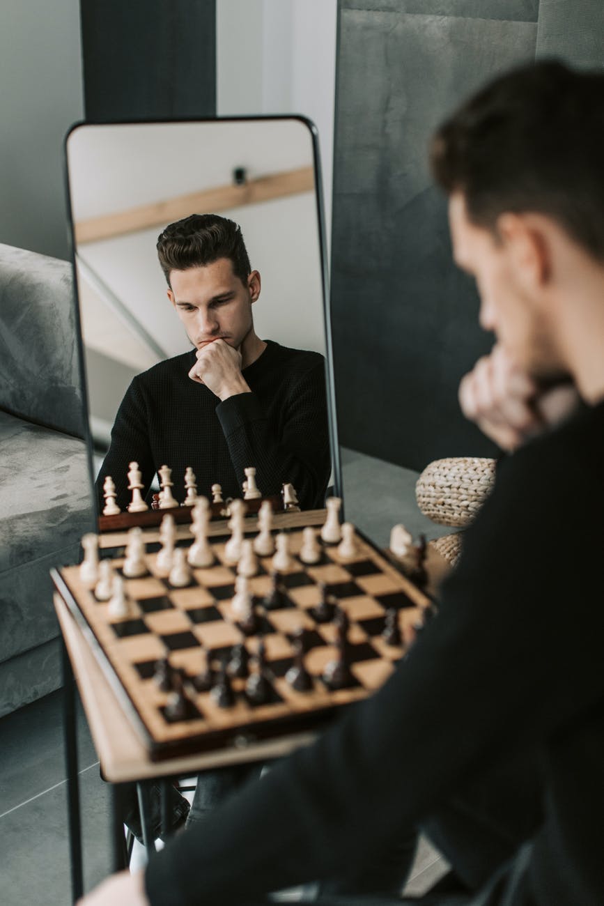 man in black sweater sitting beside chess board