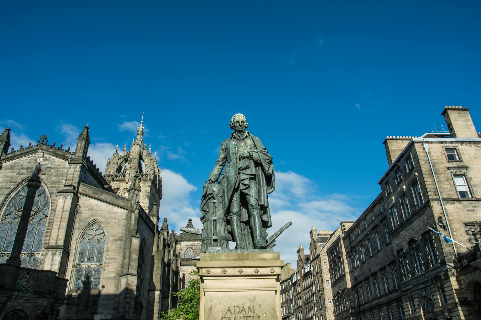 a man in coat statue near buildings under the blue sky